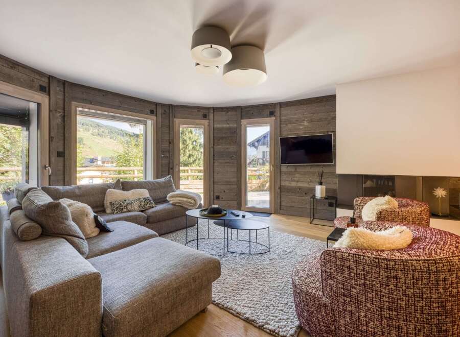 This stunning property boasts a cozy living room with a modern fireplace and a large sectional sofa, perfect for relaxing.