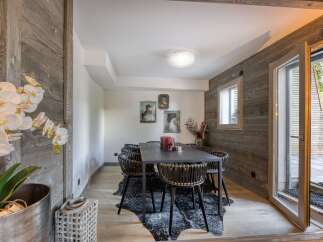 This dining room exudes rustic charm with its wood-paneled walls and a striking black dining table.
