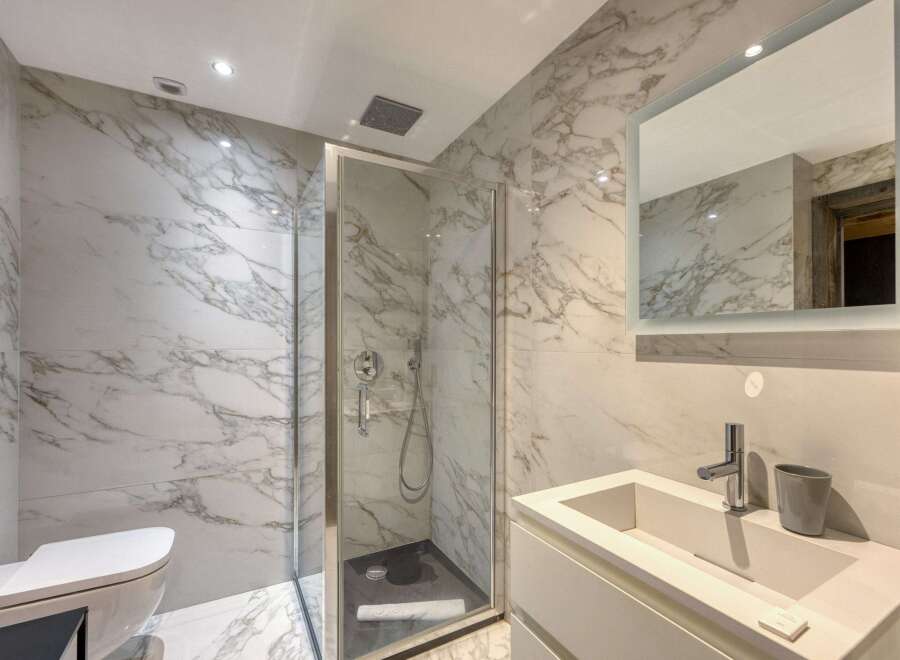 This luxurious bathroom features stunning marble walls and a modern glass shower.