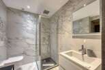 This luxurious bathroom features stunning marble walls and a modern glass shower.