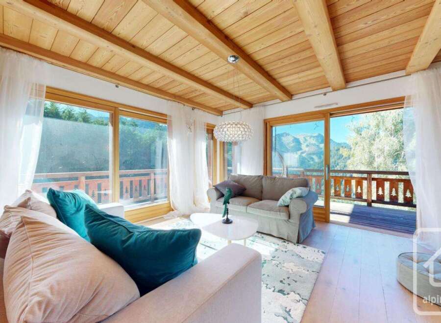 Experience the charm of this stunning property, featuring a cozy living room with a wooden ceiling and large windows.