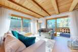 Experience the charm of this stunning property, featuring a cozy living room with a wooden ceiling and large windows.