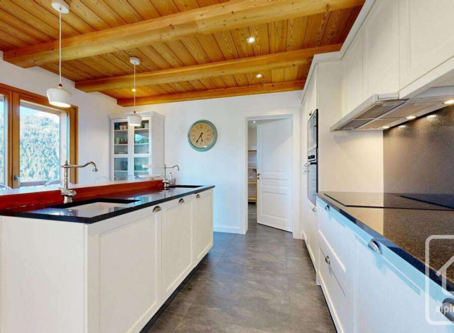 This stunning kitchen boasts a modern design with a touch of rustic charm, featuring wooden beams and sleek countertops.
