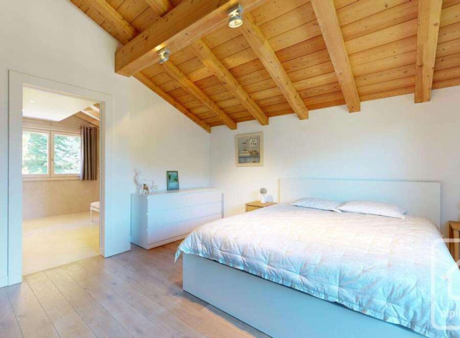 This stunning bedroom features a beautiful wooden ceiling and a cozy bed, creating a warm and inviting atmosphere.