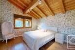This charming bedroom features a cozy ambiance with its wooden ceiling and floral wallpaper.