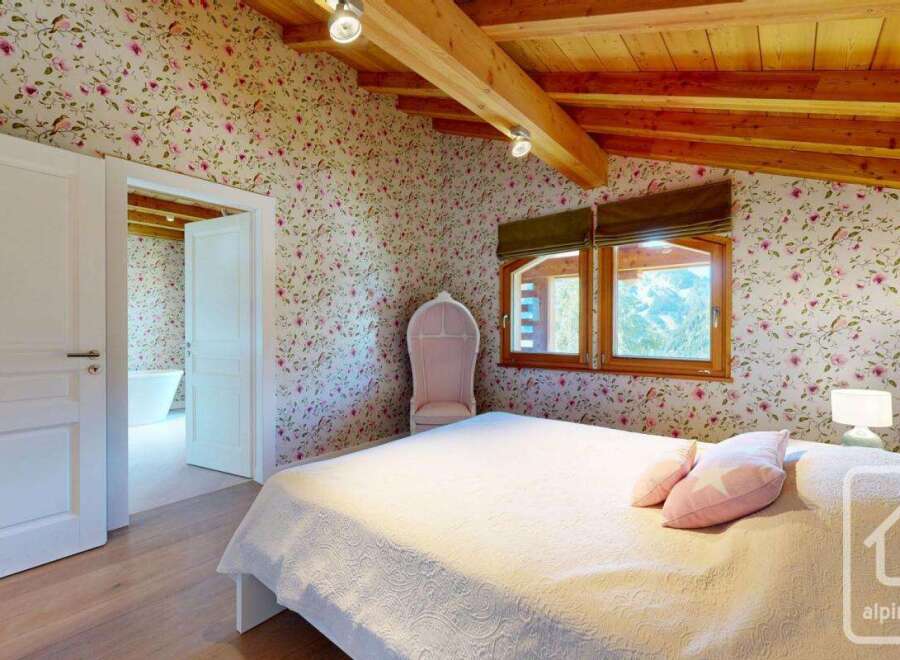 This charming bedroom features a cozy atmosphere with floral wallpaper and wooden beams.