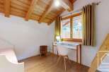 Discover the charm of this cozy bedroom, featuring a unique wooden ceiling and a bright, inviting atmosphere.