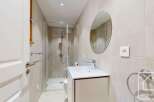 This modern bathroom features a sleek design with a glass shower enclosure, a stylish vanity, and a round mirror.