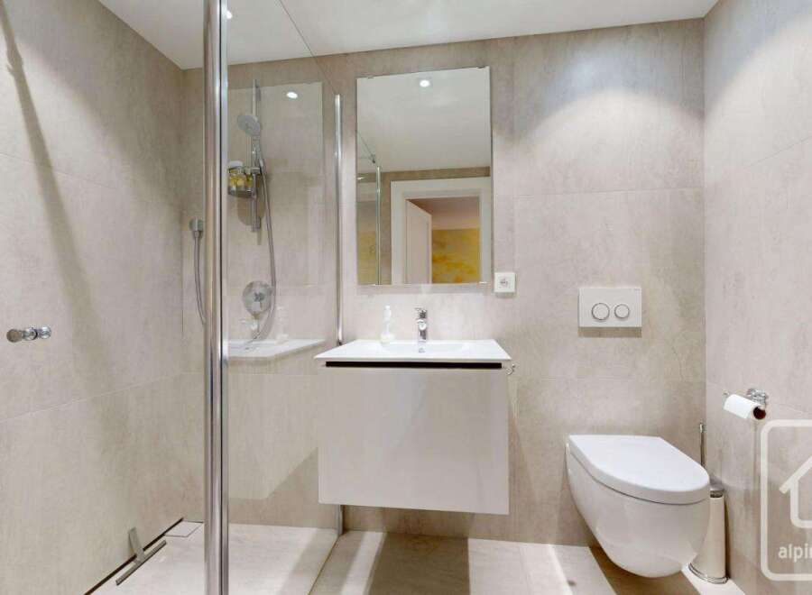 This modern bathroom features a sleek, minimalist design with neutral-toned tiles and a floating vanity.