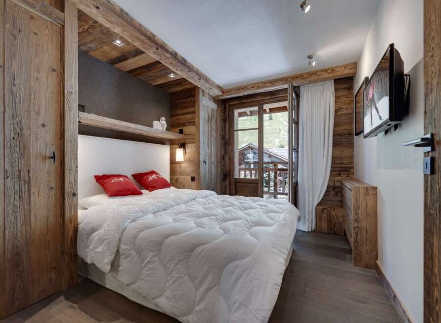 Experience rustic charm in this cozy bedroom, featuring exposed wooden beams and paneling that exude warmth.