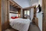 Experience rustic charm in this cozy bedroom, featuring exposed wooden beams and paneling that exude warmth.