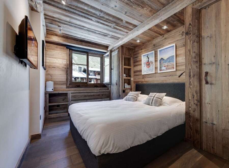 Experience rustic charm in this cozy bedroom, featuring stunning wood paneling and a comfortable bed.