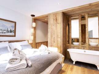 Experience luxury and comfort in this stunning bedroom featuring a cozy bed and a spa-like bathroom.