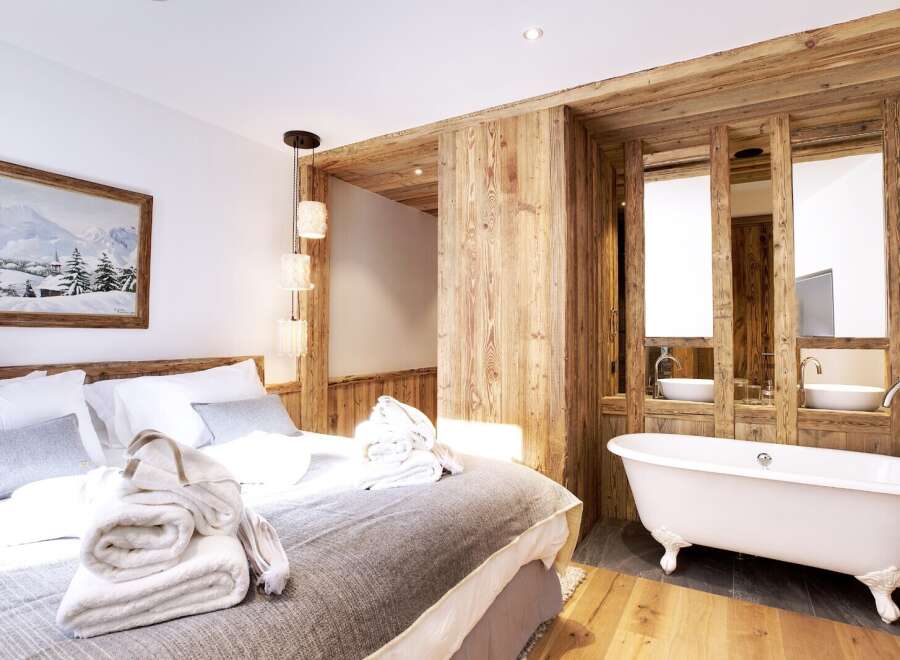 Experience luxury and comfort in this stunning bedroom featuring a cozy bed and a spa-like bathroom.