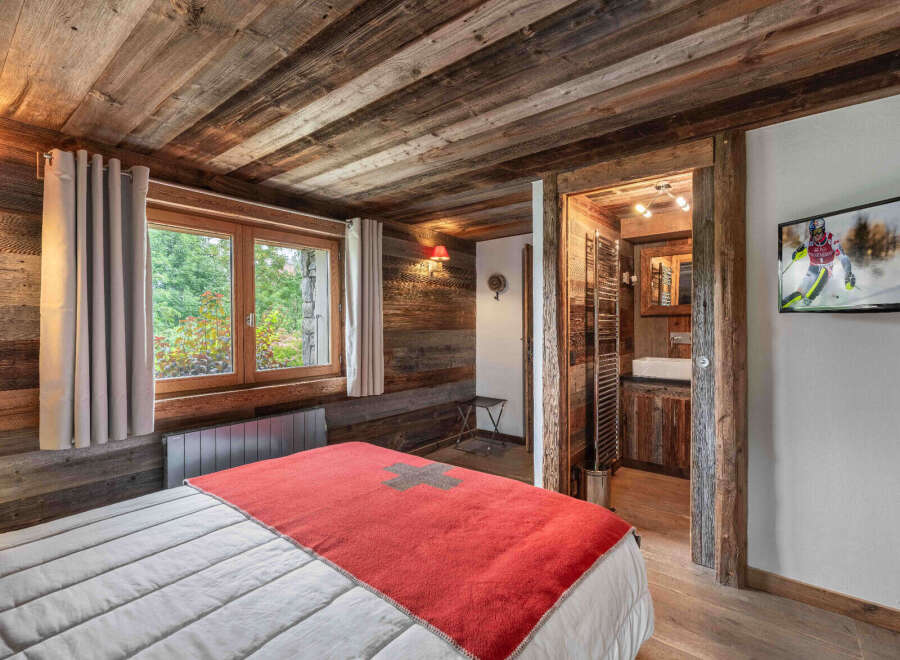 Experience rustic charm in this cozy bedroom featuring a wooden ceiling and walls, creating a warm and inviting atmosphere.