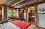 Experience rustic charm in this cozy bedroom featuring a wooden ceiling and walls, creating a warm and inviting atmosphere.