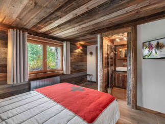 Experience rustic charm in this cozy bedroom featuring a wooden ceiling and walls, creating a warm and inviting atmosphere.