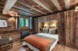 Experience rustic charm in this cozy bedroom featuring wood-paneled walls and ceiling, creating a warm and inviting atmosphere.