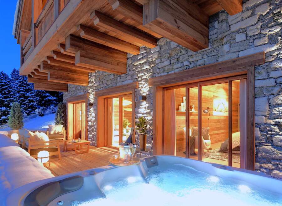 Experience luxury living in this stunning mountain chalet, featuring a private hot tub and a cozy outdoor seating area.