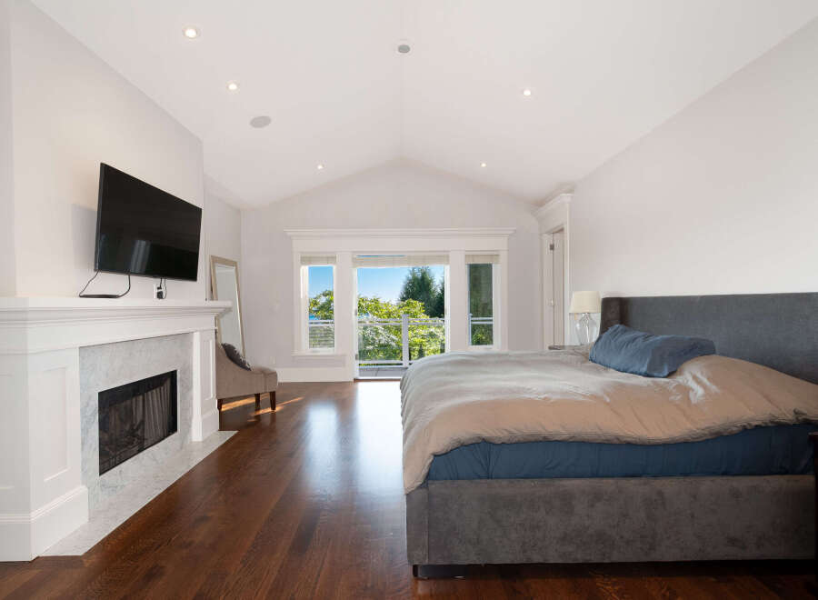 Experience luxury in this stunning bedroom featuring a cozy fireplace and a large flat-screen TV, perfect for relaxing evenings.
