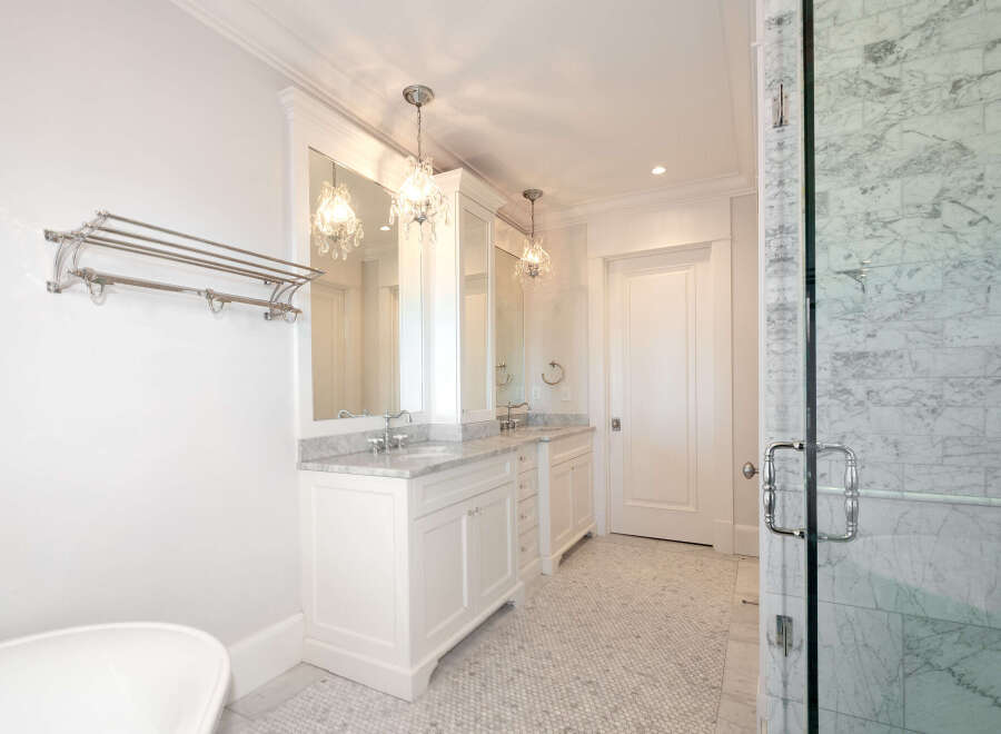 Step into luxury with this stunning bathroom featuring a double vanity, elegant crystal chandeliers, and a spacious walk-in shower.