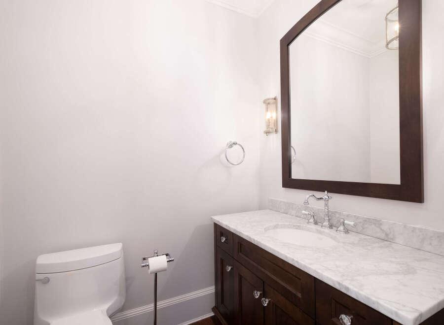 This elegant bathroom features a dark wood vanity with a marble countertop, offering a luxurious feel.