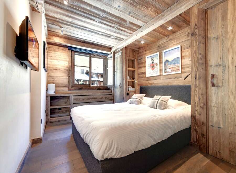 Experience the charm of this cozy bedroom, featuring rustic wooden walls and ceiling that create a warm and inviting atmosphere.
