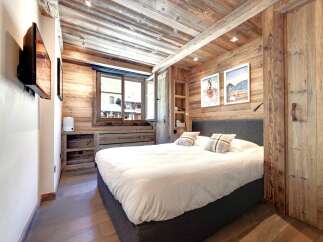 Experience the charm of this cozy bedroom, featuring rustic wooden walls and ceiling that create a warm and inviting atmosphere.