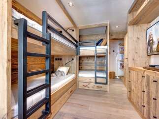 This cozy bedroom features custom-built bunk beds with a rustic wooden design, perfect for a family getaway.