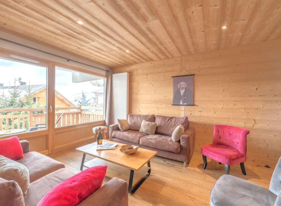 Experience the warmth of this inviting living space, featuring a cozy sofa and a charming red accent chair.