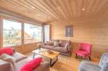 Experience the warmth of this inviting living space, featuring a cozy sofa and a charming red accent chair.