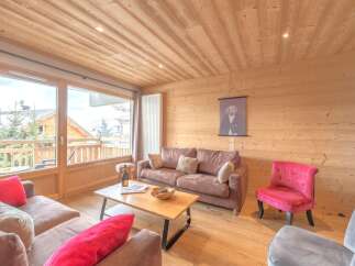 Experience the warmth of this inviting living space, featuring a cozy sofa and a charming red accent chair.
