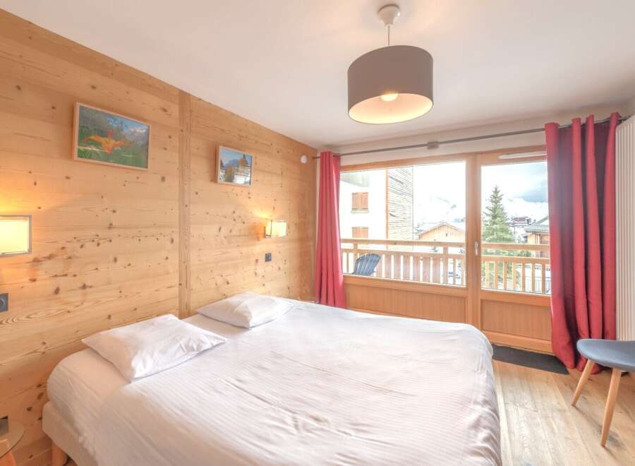 Discover the charm of this cozy bedroom, featuring a comfortable bed and a warm wooden interior.