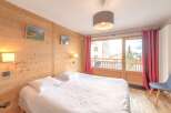 Discover the charm of this cozy bedroom, featuring a comfortable bed and a warm wooden interior.