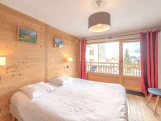Discover the charm of this cozy bedroom, featuring a comfortable bed and a warm wooden interior.