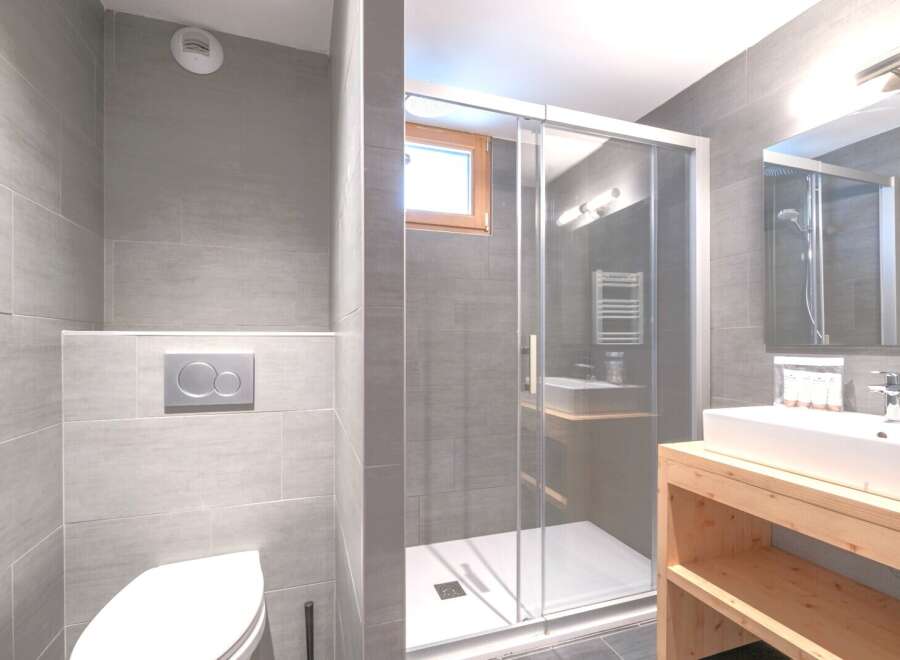 Step into a modern bathroom oasis, featuring sleek gray tile and a glass-enclosed shower.