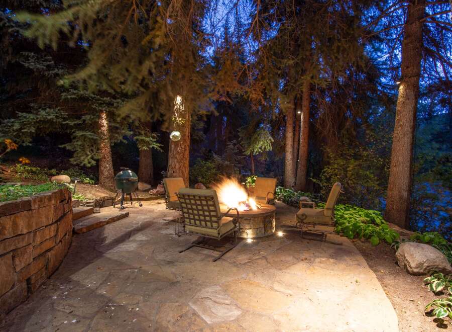 Enjoy evenings outdoors in this stunning backyard oasis, featuring a cozy fire pit and comfortable seating.