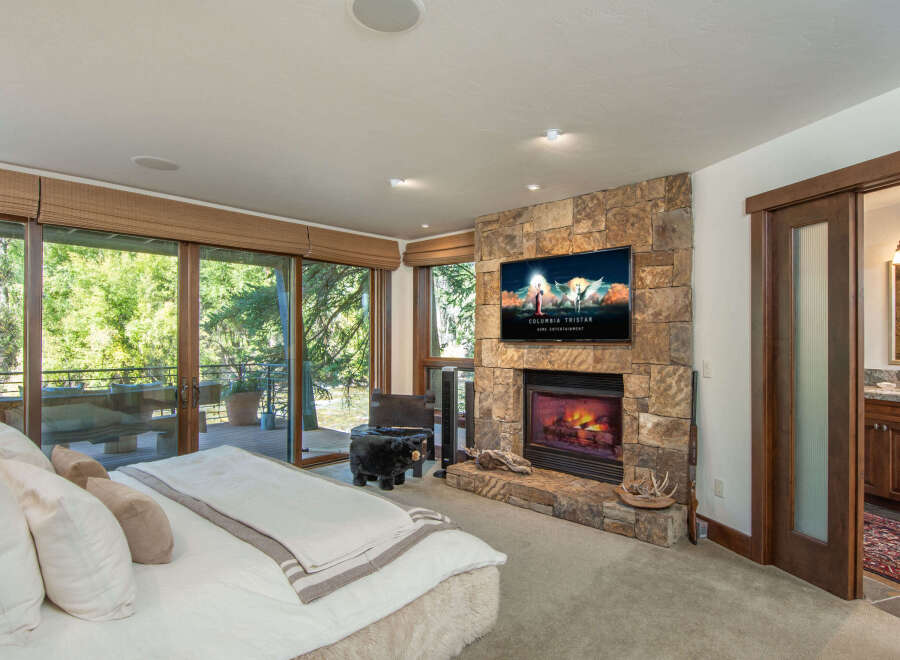 Experience luxury living in this stunning bedroom featuring a cozy fireplace and a large flat-screen TV, perfect for relaxing evenings.