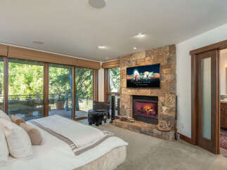Experience luxury living in this stunning bedroom featuring a cozy fireplace and a large flat-screen TV, perfect for relaxing evenings.