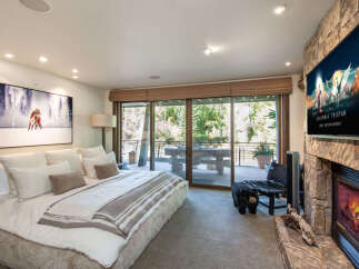 Experience luxury living in this stunning bedroom featuring a cozy fireplace and a large-screen TV for entertainment.