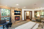 Experience luxury and comfort in this stunning bedroom featuring a cozy fireplace and a large flat-screen TV.