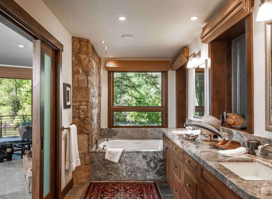 This luxurious bathroom boasts a stunning stone accent wall and a deep soaking tub, creating a spa-like retreat.
