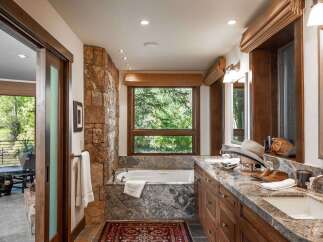 This luxurious bathroom boasts a stunning stone accent wall and a deep soaking tub, creating a spa-like retreat.