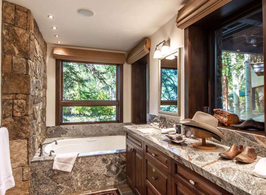 Experience luxury in this stunning bathroom featuring a natural stone accent wall and a deep soaking tub.
