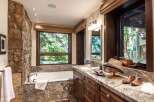 Experience luxury in this stunning bathroom featuring a natural stone accent wall and a deep soaking tub.