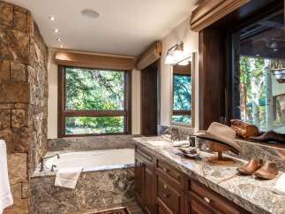 Experience luxury in this stunning bathroom featuring a natural stone accent wall and a deep soaking tub.