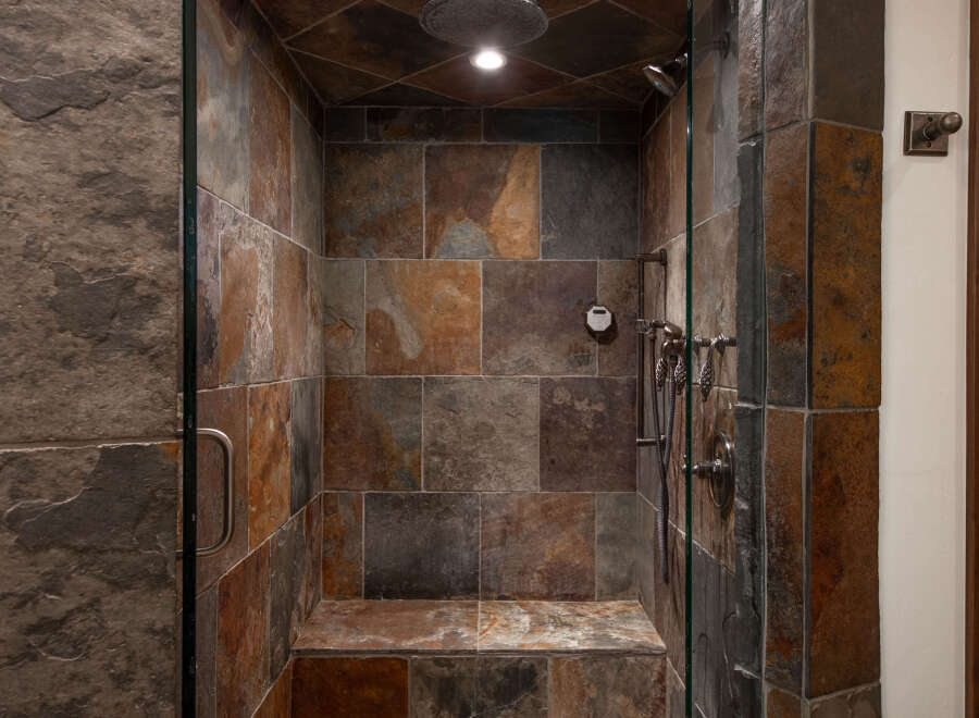 Step into luxury with this stunning shower featuring exquisite stone tile work.