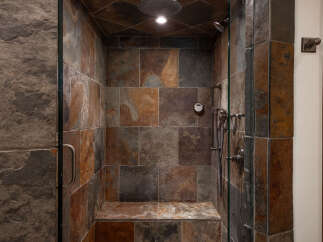Step into luxury with this stunning shower featuring exquisite stone tile work.
