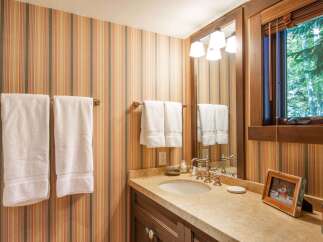This charming bathroom features a warm and inviting atmosphere with its striped wallpaper and wooden accents.