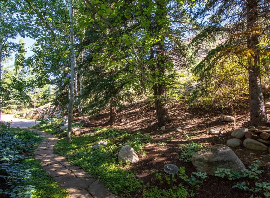 Discover the tranquility of this stunning property, featuring a beautifully landscaped pathway that winds through a lush, wooded area.